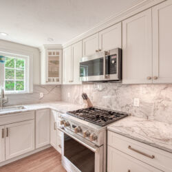 photo of stove, white kitchen cabinets and white counter top